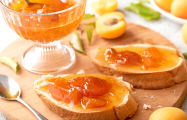 Fototapeta na wymiar Toast of bread and apricot jam with slices of fruit and fresh apricots on the table. Toasts with jam close-up. Tasty sweet breakfast.