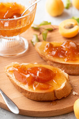 Toast of bread and apricot jam with slices of fruit and fresh apricots on the table. Toasts with jam close-up. Tasty sweet breakfast.