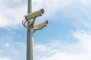 Security cameras on a concrete pole against the blue sky. 