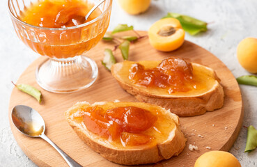 Toast of bread and apricot jam with slices of fruit and fresh apricots on the table. Toasts with jam close-up. Tasty sweet breakfast.