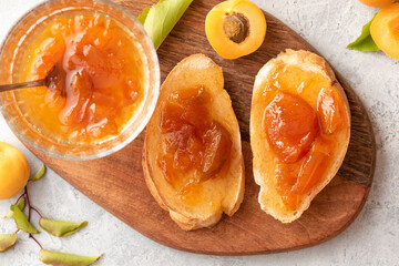 Toast of bread and apricot jam with slices of fruit and fresh apricots on a table top view. Toasts with jam close-up. Tasty sweet breakfast.