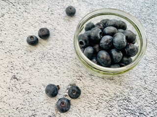 Closeup view of fresh blueberries in a small glass bowl against a natural granite textured counter in the kitchen. Juicy berries full of antioxidants.