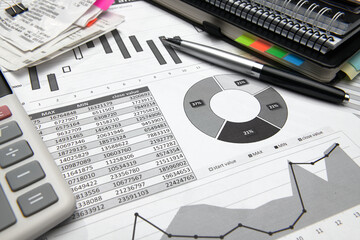business office desk closeup - financial reports, analysis and accounting, set of documents, tables and graphs, various items for bookkeeping, calculator