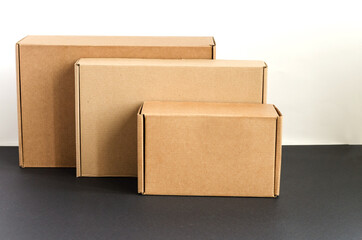 Три картонные коробки горизонтально стоят на черно-белом фоне
