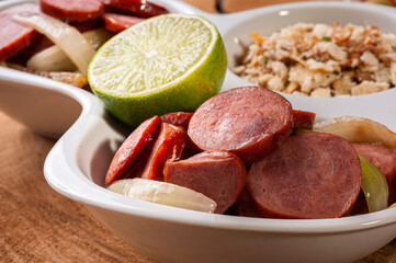 .Pepperoni sausage with onion. Very common appetizers in bars. Accompanied by farofa, pepper jelly. and lime. Selective focus