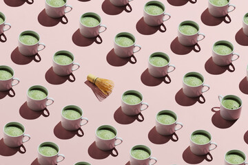 Creative pattern with cups of matcha tea and bamboo whisk chasen on pastel pink