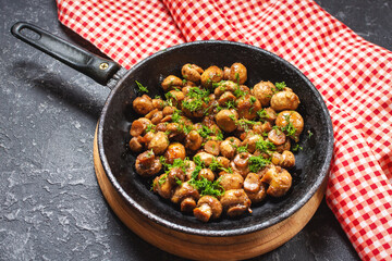 Delicious fried mushrooms in pan on stone table