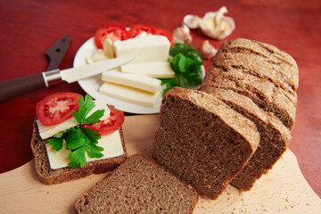 healthy food - fresh bread and feta cheese on a wooden background, tomatoes, greens and vegetables
