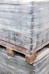 Close-up view of new red paving stones in pallets fixed with stretch wrap. Building material for the pavement reconstruction