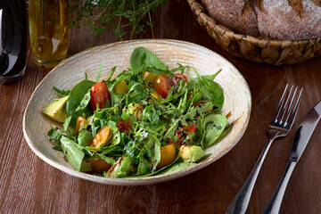 Nutritious low calorie organic vegetable salad made from green leaves and tomato and avocado seasoned with olive oil