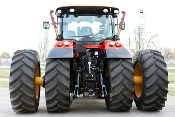Large agricultural tractor on a white background. Equipment for cultivating the land. Back view. Close-up.