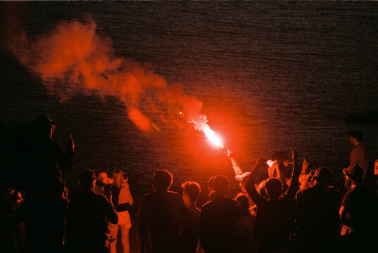 Crowd With Red Distress Flare At Night