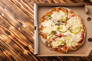 Vegetarian pizza with paprika on wholegrain dough in a cardboard box near the copy space, top view