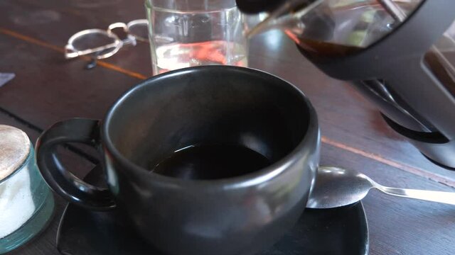 Bali coffee being poured by customer into mug at cafe in Indonesia, closeup