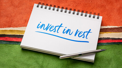 Invest in rest reminder or advice - handwriting in a spiral notebook against colorful abstract paper landscape
