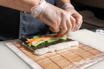 The sushi chef puts salmon on a Mat with rice and Nori