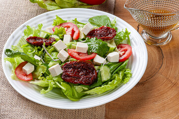 .Green salad with lettuce, arugula, cucumber, cheese and sun-dried tomatoes.