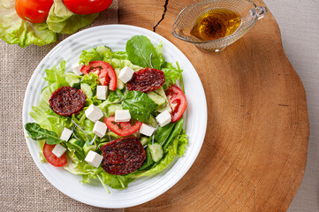 .Green salad with lettuce, arugula, cucumber, cheese and sun-dried tomatoes.