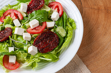 .Green salad with lettuce, arugula, cucumber, cheese and sun-dried tomatoes.