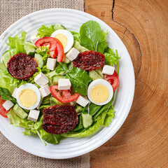 .Green salad with lettuce, arugula, cucumber, cheese, sun-dried tomatoes and boiled egg.