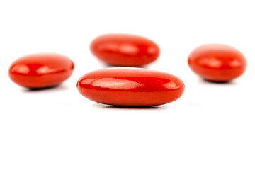 A macro shot of four red film-coated tablets arranged randomly, isolated on a white background.