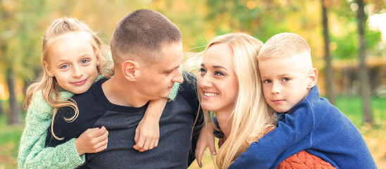Fototapeta premium Portrait of young family playing in autumn park. Parents with children resting in the autumn park