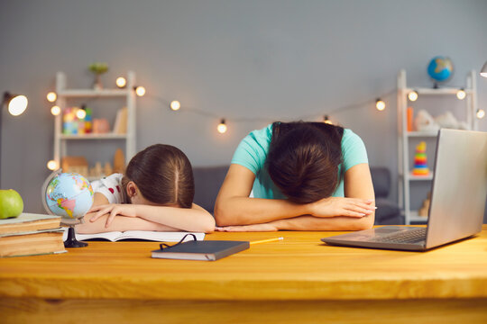 Little Girl With Her Mother Lying On Table Near Laptop Computer, Exhausted From Online Home Schooling