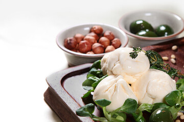 Soft mozzarella cheese on a wooden Board with green olives and nuts. Copy of the space. Top view.