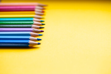 Colored pencils in Rainbow colors in a row on orange background, retro modern design space for text
