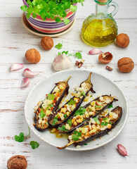 Baked eggplant with olive oil, garlic, parsley or coriander (cilantro) walnuts and bread crumbs. Vegetable Mediterranean gourmet snack in a white plate on a wooden table. Selective focus