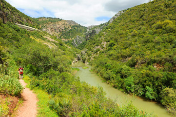 Fototapeta na wymiar Woman hiking in the Guadiaro river near the Canyon of the Buitreras -Canon de las Buitreras-, famous gorge located at the Alcornocales Natural Park, province of Malaga, Andalusia, Spain