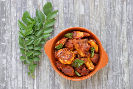 Top view of Chicken fry or Fried chicken kabab which is well garnished with curry leaves in an  earthern wares with grey background