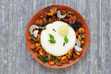 Biryani rice or Geera rice with chicken fry and prawns fry as side dish arranged in a terraccotta earthen plate with grey texture background