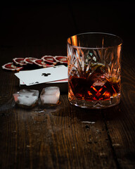 Whisky tumbler next to playing cards and poker chips