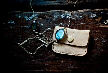 Turquoise pendant next to leather purse on wood.