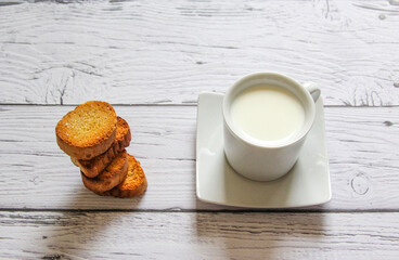 Cup of milk and bread crumbs on a wooden background. Healthy breakfast.
