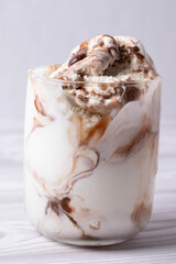 delicious creamy milky vanilla ice cream with caramel and chocolate addings in a glass container on the light rustic background