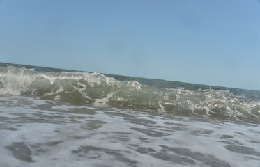 during the day the sea waves and splashes of small drops fall on the shore