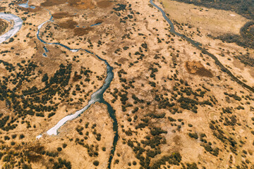 Aerial View Curved River In Early Spring Landscape. River bends Curves and dry grass landscape. Top View Of Beautiful European Nature From High Attitude. Drone View. Bird's Eye View