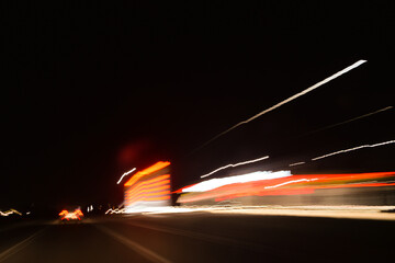 lights from headlights of cars and lights from the street lamps draw a colored track in the dark