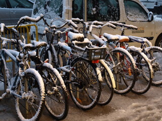 Fototapeta na wymiar Street bikes covered by the cold snow in a city