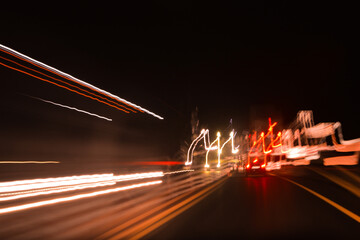 lights from headlights of cars and lights from the street lamps draw a colored track in the dark