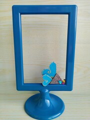 Blue rectsngual photo frame on a light blue wooden background with blue and white balls and...