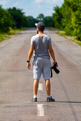 Alpha male photographer stands on the road and looks into the distance