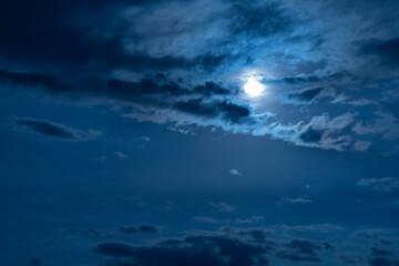 Beautiful night sky. The full moon illuminates clouds.  Nature background.