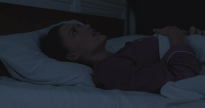 Awakened woman lying in bed having nightmare