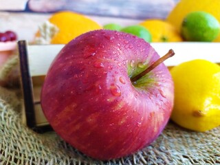Fruit and berry still life yellow oval melon orange lemon red apple green unripe walnuts and yellow rowan in a wooden box on the kitchen table