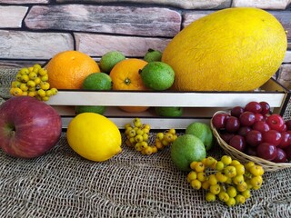 Fruit and berry still life yellow oval melon orange lemon red apple green unripe walnuts and yellow rowan in a wooden box on the kitchen table
