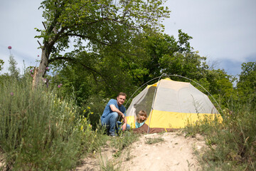 Happy family dad and child on camping trip relaxing inside tent. Staycations, hyper-local travel,  family outing, getaway.