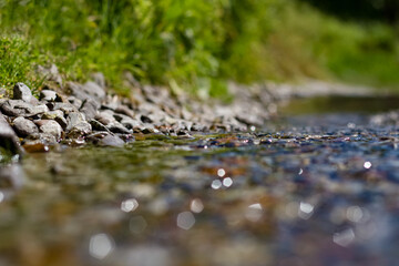 a stream flows along the street, a sewer breakthrough, water flows between stones and grass